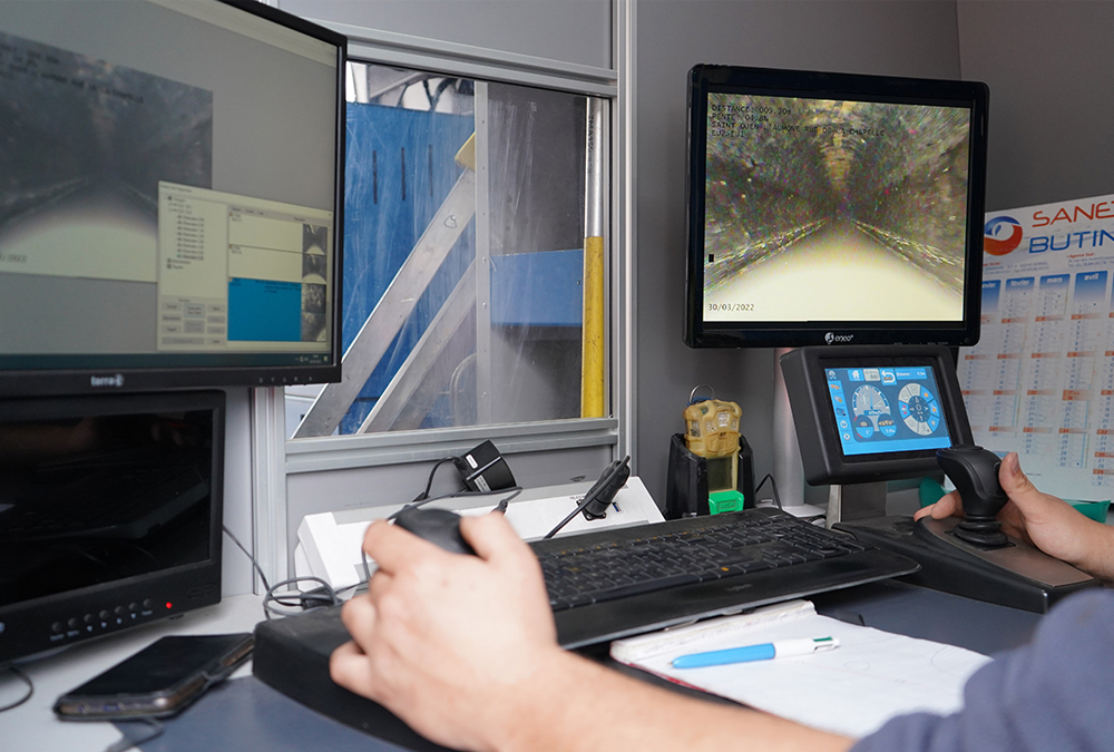 Agent visualisant son écran et observant l'inspection télévisée de l'intérieur d'une canalisation du réseau d'assainissement