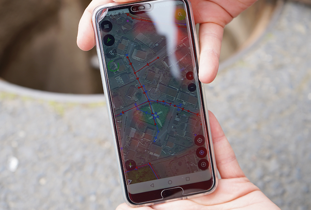 Application Qfield sur un téléphone portable permettant de visualiser les réseaux d'assainissement dans un quartier
